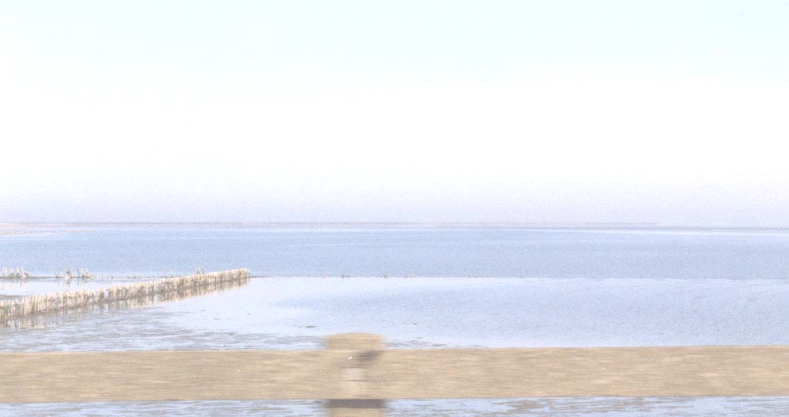 Wolken brechen Sonnenstrahlen Artwork: Blick über Holzgeländer aufs Wattenmeer